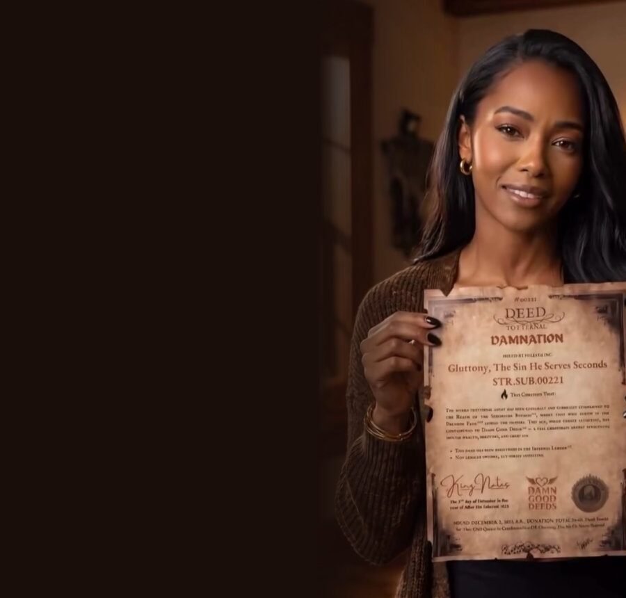 Smiling woman holding a HellYea Plots Deed of Damnation