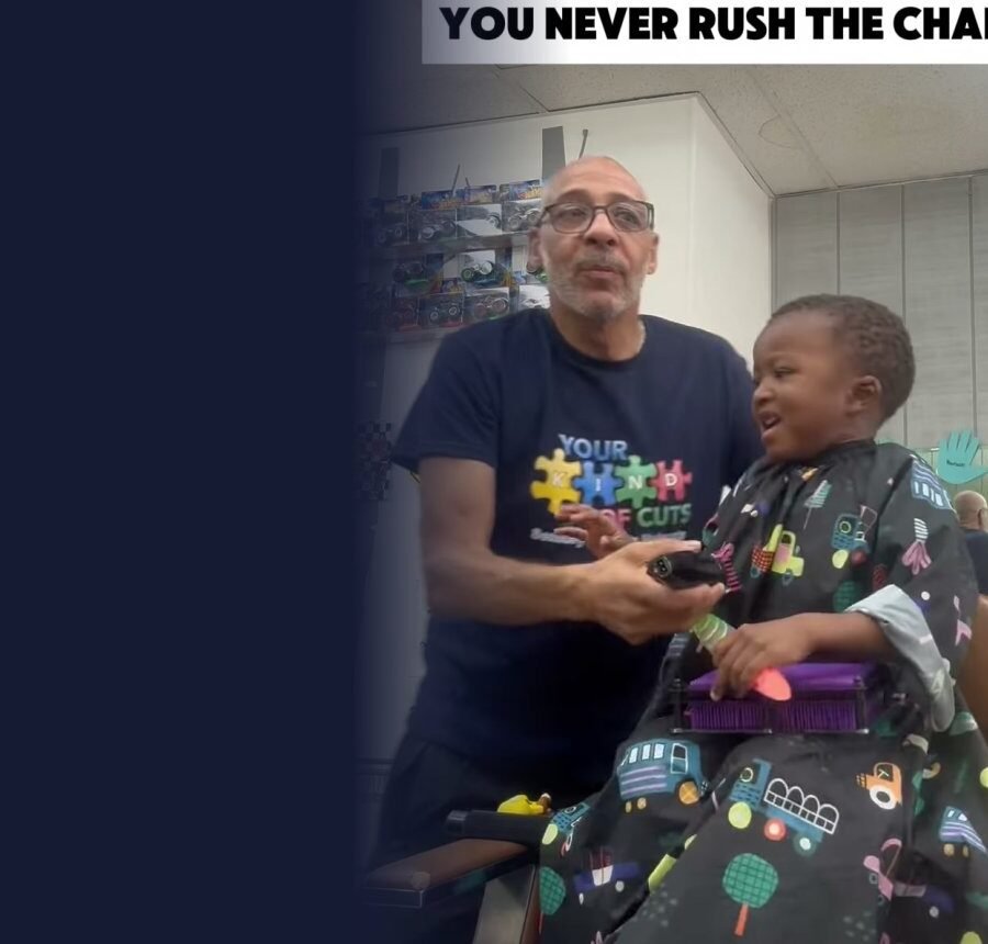 Smiling barber in a Your Kind of Cuts shirt giving a calm haircut to a happy young client